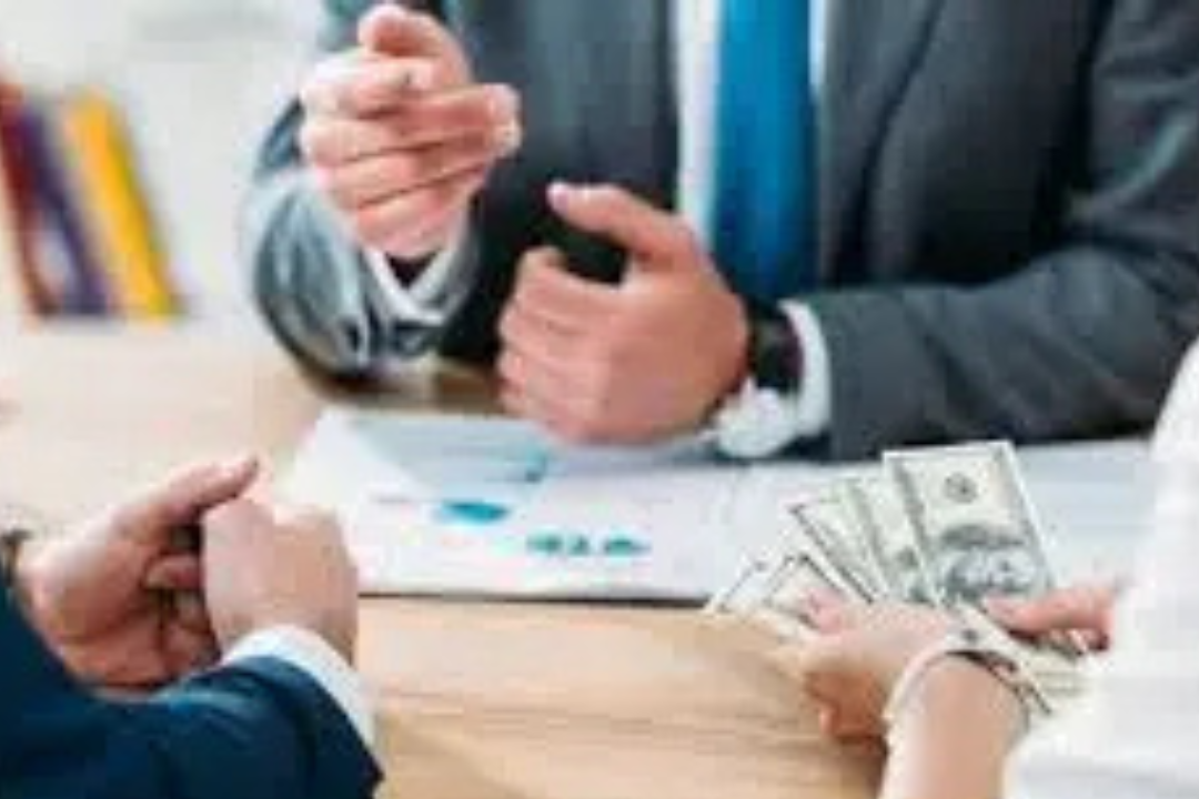 1. A group of business professionals seated around a table, discussing best crypto singnal with stacks of money in front of them.